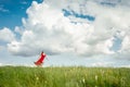 Beautiful happy woman in red dress runs on a green field Royalty Free Stock Photo