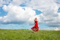 Beautiful happy woman in red dress stand on green grass Royalty Free Stock Photo