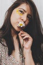 Beautiful happy woman with yellow petals under eyes posing in sunny room. Portrait of young brunette female in boho dress smiling Royalty Free Stock Photo