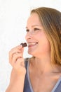 A beautiful happy 35 years blonde woman with a chocolate candy in her hand. Close up portrait with copy space