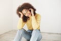 Beautiful happy young african dark-skinned girl with curly afro hairstyle wearing yellow turtleneck and jeans, smiling