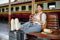 A beautiful Asian female traveler is using her smartphone while resting on a bench Royalty Free Stock Photo