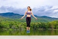 Beautiful happy young Asian woman jumping rope during her morning exercise at a lake with mountains background Royalty Free Stock Photo