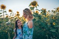 Beautiful happy young blonde mom and her brunette teen daughter smiling and looking at each other, standing among the Royalty Free Stock Photo