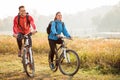Beautiful happy young couple enjoying early morning bicycle ride by the river or lake