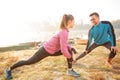 Beautiful happy young couple exercising, stretching in the early morning mist on the lake or river banks Royalty Free Stock Photo