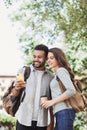 Beautiful happy young couple using smartphone outdoors. Joyful smiling woman and man looking at mobile phone in a city