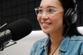 Beautiful happy young woman radio host using microphone and headphones while broadcasting in studio Royalty Free Stock Photo