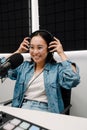 Beautiful young female radio host using microphone and headphones while broadcasting in studio Royalty Free Stock Photo