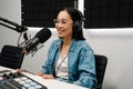 Young female radio host using microphone and headphones in studio Royalty Free Stock Photo