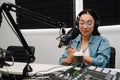 Young female radio host using microphone and headphones in studio Royalty Free Stock Photo