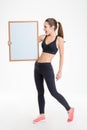 Beautiful happy young fitness woman in tracksuit showing blank board Royalty Free Stock Photo