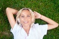 Beautiful happy young girl with headphones listening to music lying on grass looking at camera. Royalty Free Stock Photo