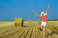 Beautiful happy young girl jumping for joy in the air near a haystack Royalty Free Stock Photo