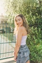 A beautiful happy young girl posing against a fence on sunlight Royalty Free Stock Photo