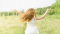 Beautiful and happy young girl running on the green field in a white dress. Royalty Free Stock Photo