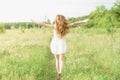 Beautiful and happy young girl running on the green field in a white dress. Royalty Free Stock Photo