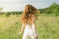 Beautiful and happy young girl running on the green field in a white dress. Royalty Free Stock Photo