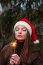 Beautiful happy young girl with Santa Claus hat. Holding sparklers. Girl makes a Christmas wish Royalty Free Stock Photo