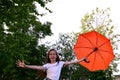 beautiful happy young girl in white T-shirt holds an orange umbrella, having fun on sunny summer day outdoors against background Royalty Free Stock Photo