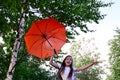 beautiful happy young girl in white T-shirt holds an orange umbrella, having fun on sunny summer day outdoors against background Royalty Free Stock Photo