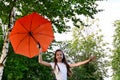 beautiful happy young girl in white T-shirt holds an orange umbrella, having fun on sunny summer day in park against the Royalty Free Stock Photo
