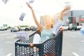 Beautiful young vietnamese girl sitting in the market trolley and scattering cash. Shoppinh concept.