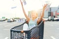 Beautiful young vietnamese girl sitting in the market trolley and scattering cash. Shoppinh concept.