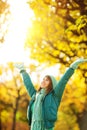 Beautiful happy young woman in the autumn park. Joyful woman wearing bright teal hat and scarf is having fun outdoors in a bright