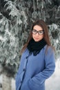 Beautiful happy young woman with black glasses wearing winter coat color Blue Cobalt and black scarf covered with snow Royalty Free Stock Photo