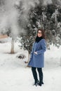 Beautiful happy young woman with black glasses wearing winter coat color Blue Cobalt and black scarf covered with snow Royalty Free Stock Photo