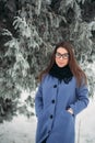 Beautiful happy young woman with black glasses wearing winter coat color Blue Cobalt and black scarf covered with snow Royalty Free Stock Photo