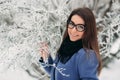 Beautiful happy young woman with black glasses wearing winter coat color Blue Cobalt and black scarf covered with snow Royalty Free Stock Photo