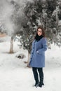 Beautiful happy young woman with black glasses wearing winter coat color Blue Cobalt and black scarf covered with snow Royalty Free Stock Photo