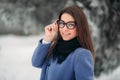 Beautiful happy young woman with black glasses wearing winter coat color Blue Cobalt and black scarf covered with snow Royalty Free Stock Photo