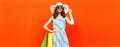 Beautiful happy young woman with colorful shopping bags wearing dress and summer straw hat in the city Royalty Free Stock Photo