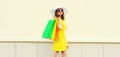 Beautiful happy young woman with colorful shopping bags wearing yellow dress and summer straw hat in the city Royalty Free Stock Photo