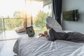 Beautiful happy young woman in a gray bathrobe and with a towel on her head on a bed in a hotel room working on a laptop, vacation Royalty Free Stock Photo