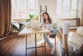 Beautiful happy young woman hipster designer working on a project using laptop and blueprints in rolls at home in apartment Royalty Free Stock Photo
