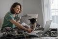 Beautiful happy young woman at home having breakfast on bed in pajamas in front of laptop with african terrier bassenji dog Royalty Free Stock Photo