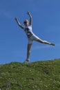 Pretty blonde in sunglasses in a white T-shirt and shorts jumping high in air, against background of summer blue sky. Royalty Free Stock Photo