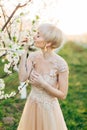 Beautiful happy young woman in luxury elegant wedding dress enjoying smell in a flowering spring garden. Spring blooming Royalty Free Stock Photo