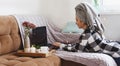 Beautiful happy young woman in a plaid shirt and with a towel on her head on a bed in a hotel room working on a laptop, vacation Royalty Free Stock Photo