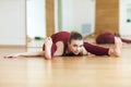 Beautiful happy young woman in red sportswear working out indoors. Girl sitting in Wide-Angle Seated Forward Bend pose, Upavishtha