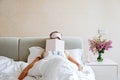 Beautiful Happy Young Woman sleeping with notebook In Bed. Portrait Of stlish Blonde Girl with blindfold in bedroom Royalty Free Stock Photo