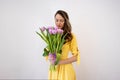 Beautiful happy young woman smiling with a bouquet of flowers of pink tulips on a white background. The girl smells Royalty Free Stock Photo