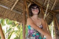 Beautiful happy young woman in sunglasses sitting in a wooden gazebo at sunny day. Tropical Bali island, Indonesia. Royalty Free Stock Photo