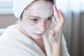 Happy woman applying cream on face moisturizing the skin. Concept of hygiene and care for the skin at home