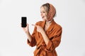 Beautiful happy young woman wearing silk scarf isolated over white background showing display of mobile phone