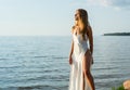 Beautiful happy young woman in a white dress enjoying the sun at sunset at sea background Royalty Free Stock Photo